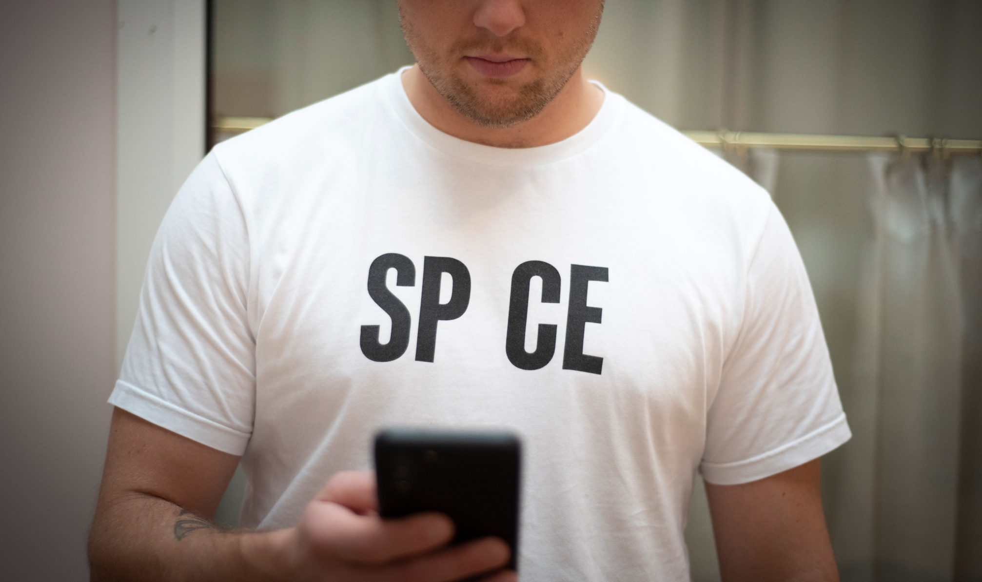 A SP_CE team member standing with phone in a SP_CE t-shirt
