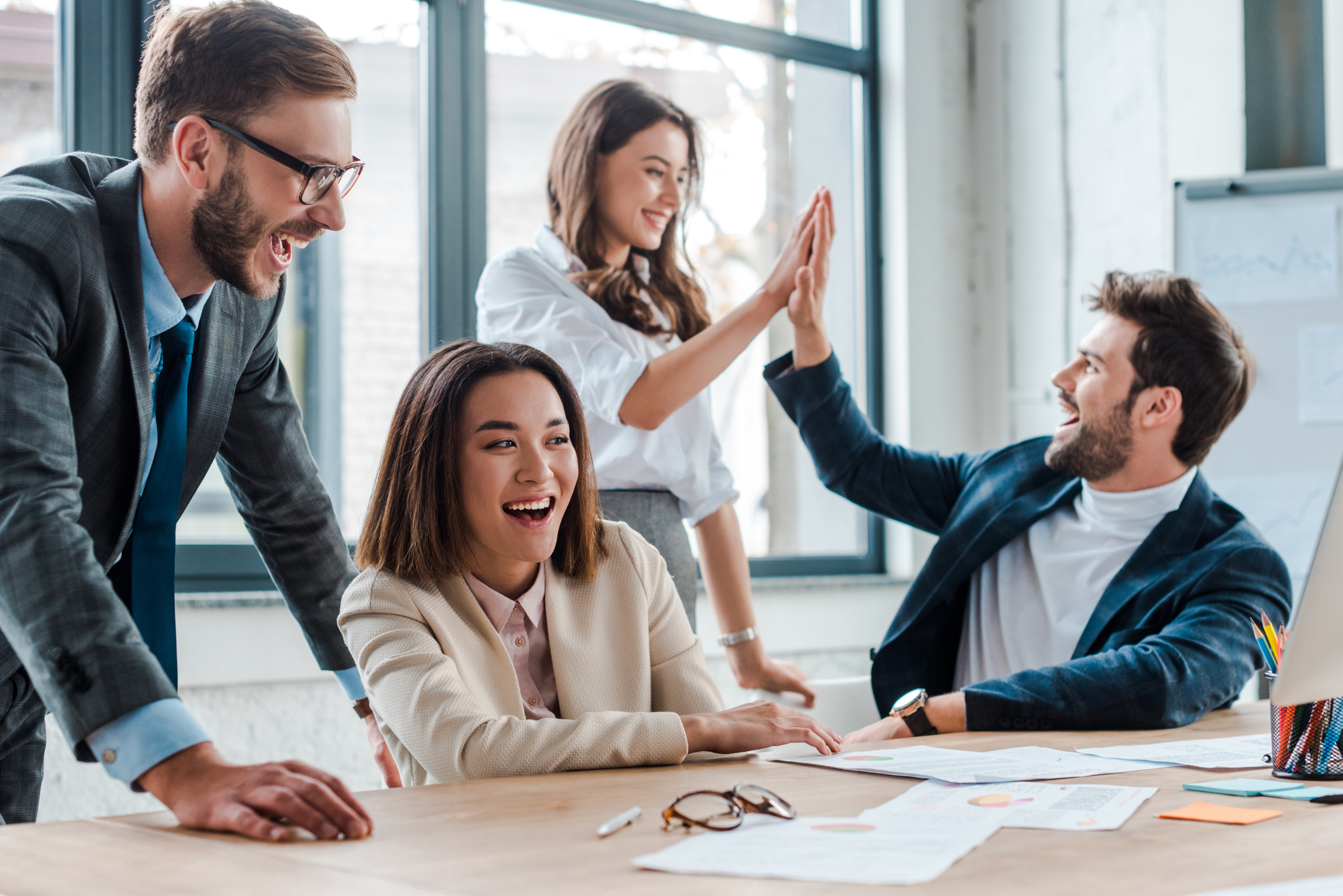 diverse partners high-fiving in office celebrating indirect sales success