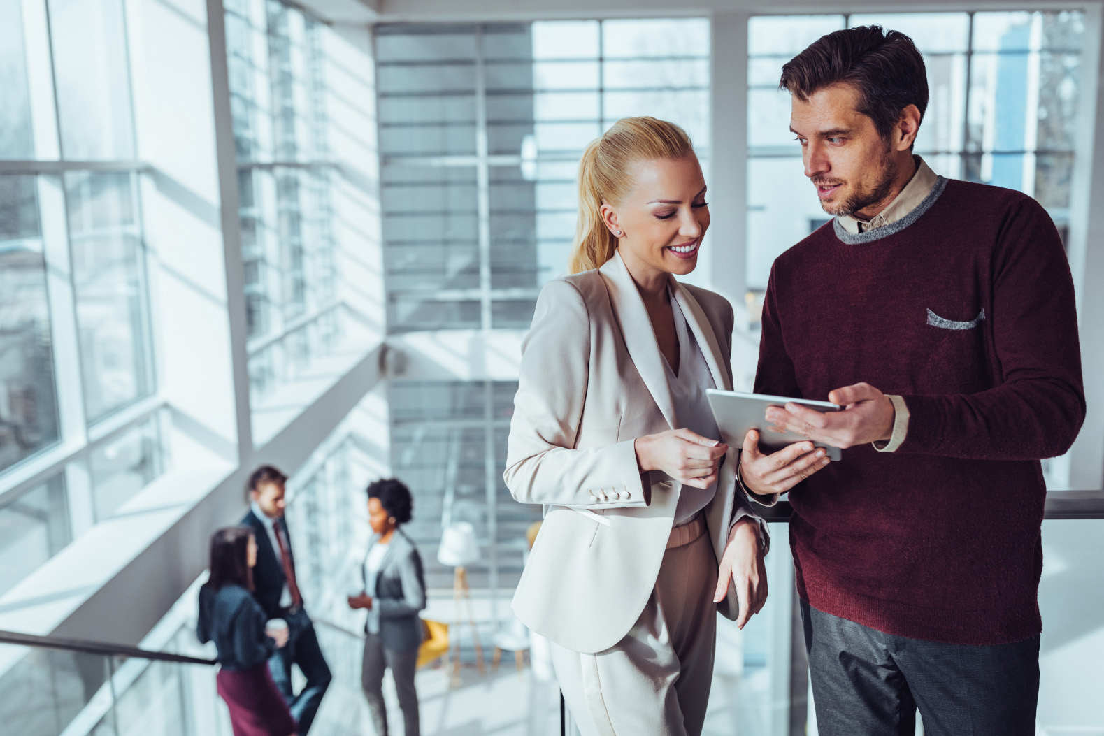 happy male and female channel partners looking at tablet in stylish office