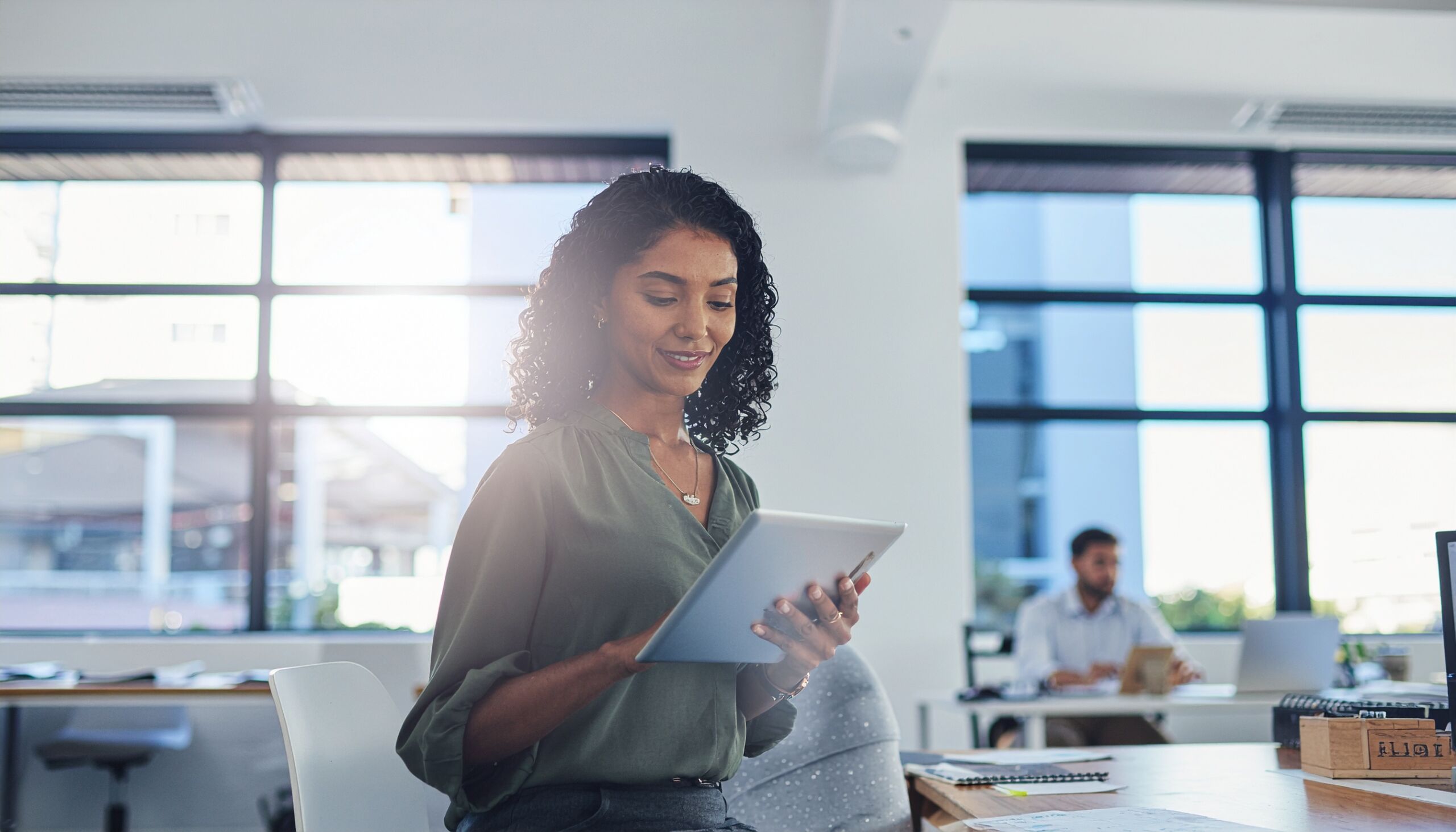 Channel sales CEO using a tablet in a bright office, working with an AI assistant
