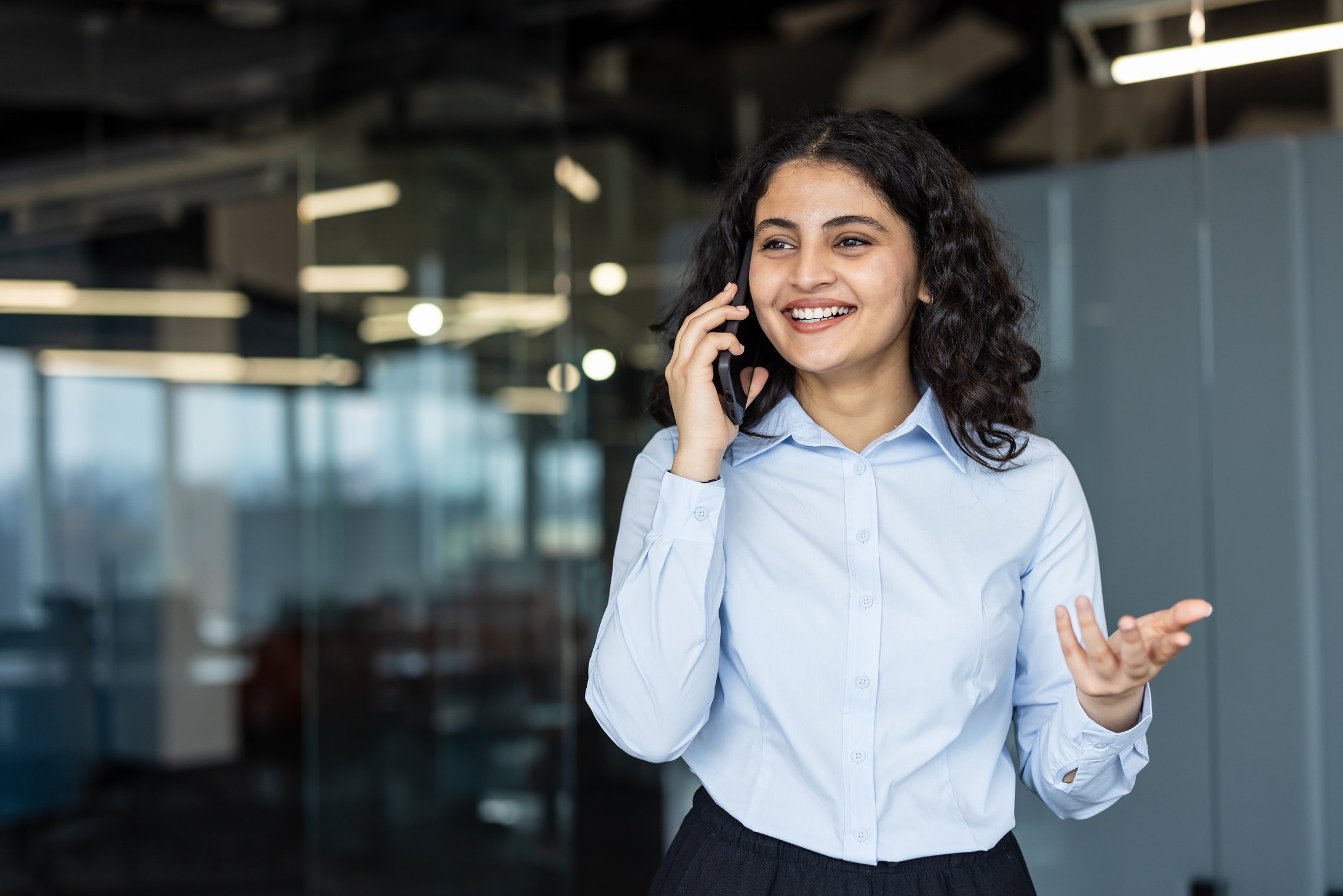 female millennial channel manager, standing in a modern office, calling a channel partner to reactivate them