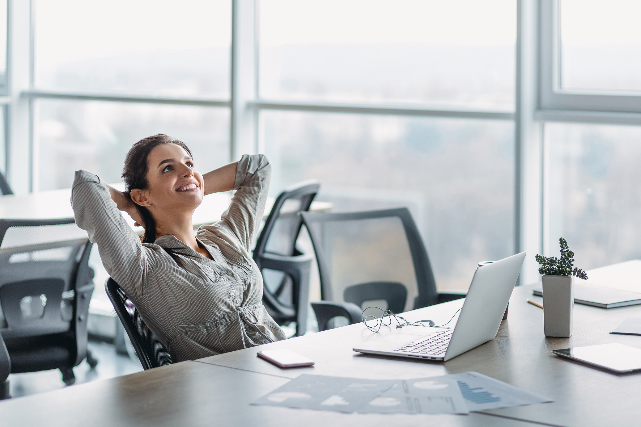 female cmo in bright office taking a moment to relax by her desk after successfully solving the content chaos that was previously pretty bad